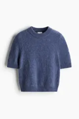 Top corto azul de punto suave con lana y mohair en la trama. Modelo de manga corta con cuello redondo ribeteado acanalado y remate acanalado en puños y bajo.