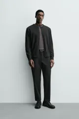 Pantalón de corte regular fit, color negro, confeccionado en tejido elástico. Presenta cintura elástica, cierre frontal con cremallera y botón, bolsillos laterales y bolsillos traseros de vivo.