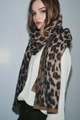 Pañuelo rectangular de tejido jacquard con estampado animal print en tonos marrones y beige, con terminaciones deshilachadas en los extremos.