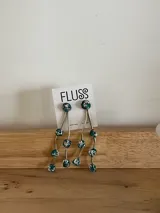 Caravanas colgantes de bronce con diseño de tres hilos ondulados, adornados con pequeñas piedras turquesas con incrustaciones plateadas. Incluye un brazalete a juego con el mismo diseño de piedras.