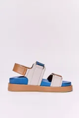 Sandalias bajas de cuero con plataforma, base color suela, plantilla azul y tiras de cuero en color beige, blanco y azul.