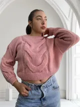 Sweater tejido de punto grueso color rosa con diseño de trenzas en el frente y mangas abullonadas.