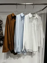 Camisa de corte oversize color marrón, con cuello clásico, cierre frontal de botones y mangas largas con puños ajustables. Presenta un diseño de hombros caídos y un bolsillo frontal en el pecho.