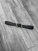 Cinto negro de cuero con hebilla doble entrelazada plateada.