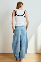 Jeans de tiro medio y diseño balloon, color azul denim con efecto lavado, cinco bolsillos, cierre frontal con cremallera y botón metálico, y bajos acabados en puño.