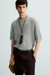 Camiseta de punto calado, color gris claro, de corte relajado (relaxed fit), con cuello redondo y mangas cortas.