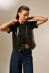 Chaleco negro de eco-cuero con textura de cocodrilo, corte entallado y cierre frontal con botones metálicos.