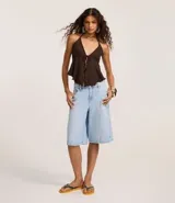 Bermuda tipo jorts de jeans, tiro medio/alto, color celeste claro lavado, corte ancho y largo que llega por encima de la rodilla. Presenta cinco bolsillos y trabillas para cinturón.