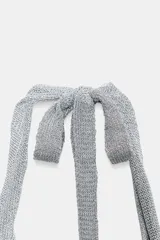 Top halter de punto con hilo metalizado, color plateado, con escote pronunciado y tirantes para anudar al cuello.