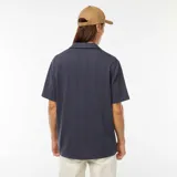 Camisa azul de manga corta con cuello cubano y cierre frontal con botones. Tejido de punto calado con diseño de espiga.