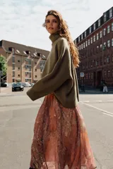 Falda midi de corte fluido con estampado paisley en tonos naranja, rosado y beige. Presenta cintura elástica y viene acompañada de un cinturón de cuero sintético marrón con hebilla metálica. Incluye forro interior.