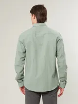 Camisa de manga larga color verde claro, con cuello clásico y cierre frontal con botones.