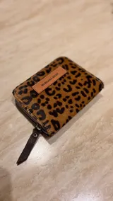 Billetera de cuero de pelo con estampado animal print de leopardo. Cuenta con cierre perimetral y una etiqueta de cuero con el logo de la marca grabado.