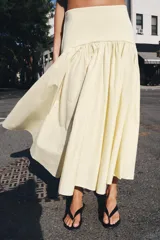 Falda de tiro medio color amarillo claro, confeccionada en tejido de punto elástico con detalle de aplicación combinada y bajo en línea evasé. Cuenta con cierre lateral con cremallera oculta.