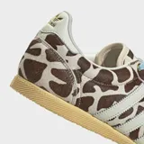 Championes Adidas modelo Japan con diseño de perfil bajo, exterior de cuero con acabado de pelo de poni y estampado animal print tipo jirafa. Presenta las icónicas tres tiras laterales en blanco, cordones en color celeste y suela de caucho en tono amarillento.