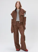 Campera de denim a rayas verticales con cuello de pana en color bordó. Presenta cierre frontal, mangas desmontables con cierre en los hombros, canesú en el pecho y bolsillos de parche cuadrados.