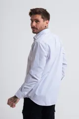 Camisa de vestir de corte regular, con diseño de rayas verticales finas en color azul sobre fondo blanco, cuello clásico y mangas largas con puños abotonados.