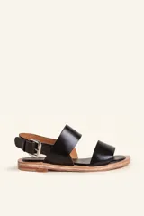 Sandalias planas de cuero negro con tiras anchas en el empeine y cierre ajustable con hebilla metálica en el talón.