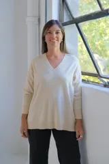 Sweater de punto color crudo, con escote en V, manga larga y diseño holgado con costura central vertical.