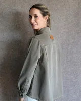 Sobrecamisa de denim azul con cuello camisero, cierre frontal con botones, mangas largas con puños abotonados y dos bolsillos con solapa en el pecho.