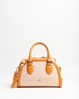 Cartera tipo baúl color tostado con cuerpo de lona y detalles en cuero sintético, asas de mano y correa larga regulable extraíble.