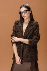 Blazer de corte estructurado confeccionado en tejido jacquard con estampado ornamental en tonos marrones. Presenta solapas clásicas, cierre frontal y diseño de manga larga.