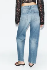 Jeans wide leg de tiro alto y cinco bolsillos, confeccionados en denim con lavado azul medio y efecto desgastado. Presenta cierre frontal con cremallera y botón metálico.