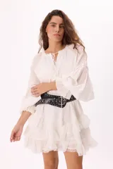 Vestido corto blanco de voile con volados en capas y detalles de puntilla. Escote con lazo y manga amplia para un estilo boho romántico.