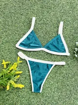 Conjunto de bikini verde esmeralda con ribetes blancos, compuesto por un corpiño triangular fijo con abertura para agregar tazas soft y una bombacha colaless regulable.