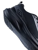 Championes deportivos Umbro modelo Void, color negro con detalles en gris oscuro. Presentan una estructura de malla transpirable, suela robusta con amortiguación y el logo de la marca en el lateral y la lengüeta.