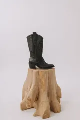 Botas tejanas de cuero negro con caña alta, taco cuadrado y delicadas costuras en contraste que forman diseños bordados en el cuerpo y empeine.