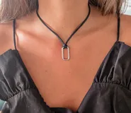 Collar doble con cadena de cuero sintético negro y dije rectangular plateado.