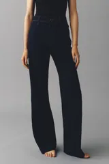 Jean wide leg de tiro alto en denim azul oscuro con costuras en tono contraste, trabillas para cinto y cierre frontal con botón metálico.
