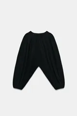 Top corto negro de punto fino, con cuello redondo y mangas largas abullonadas con pliegues.