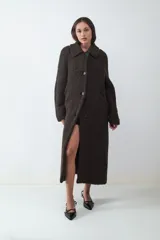 Tapado largo estilo shearling de textura rizada, con cuello camisero y cierre frontal de botones. Presenta un diseño envolvente de calce relajado y estructura voluminosa.