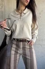 Sweater de punto color beige, con cuello polo y cierre frontal de botones, de manga larga con puños elásticos y diseño texturizado de rombos.