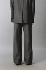 Pantalón de traje relaxed fit en color gris oscuro con diseño de espiga. Cuenta con bolsillos frontales, bolsillos traseros de vivo y cierre frontal con cremallera y botón.