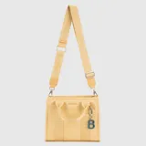 Tote bag color amarillo, con diseño compacto y funcional. Cuenta con doble asa de mano, correa ajustable y extraíble con logo de la marca, cierre principal y un dije colgante con forma de letra B.