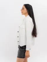 Campera de jean blanca con bolsillos frontales con solapa y botones metálicos oscuros.