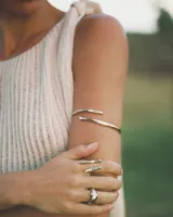 Brazalete rígido de diseño minimalista con forma de espiral, elaborado artesanalmente en bronce y alpaca maciza. Es una pieza ajustable que puede lucirse tanto en el antebrazo como en la parte superior del brazo.