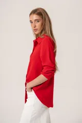 Camisa clásica de manga larga en color bordó, confeccionada en tela ligera con caída fluida, cuello camisero y cierre frontal con botones al tono.