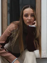 Buzo de tejido de punto con cuello alto, diseño color block en tonos beige, bordó y rosa viejo, con mangas largas y puños en contraste.