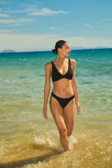 Conjunto de bikini negro de lycra texturada, compuesto por un corpiño triangular fijo con elástico interno bajo el busto y una bombacha vedetina con elástico interno.