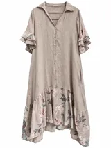 Vestido midi color beige de lino, con cierre frontal de botones, cuello camisero, mangas cortas con volados escalonados y detalle de volado estampado con flores en el ruedo.