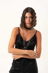 Top de satén negro con escote en V, decorado con detalles de encaje floral en el escote y en el ruedo. Presenta breteles finos ajustables y un corte asimétrico en la parte inferior.