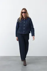 Campera de jean color negro con cuello de pana en tono marrón, cierre frontal con botones metálicos y bolsillos frontales tipo cargo.