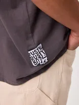 Remera gris oscuro de manga corta, con calce holgado y gran estampado en la espalda de una lata de refresco con la inscripción "Rusty Soda Club".