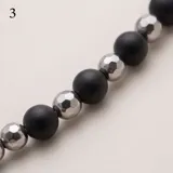 Pulsera de acero con diseño de cuentas alternadas de piedras naturales negras y esferas metálicas plateadas.