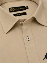 Camisa beige de algodón con tejido twill, corte slim fit, cuello camisero clásico y botones frontales con costuras oscuras.