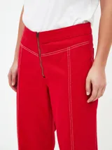 Pantalón de corte recto y tiro alto, color rojo, con costuras decorativas en contraste y cierre frontal con cremallera expuesta.
